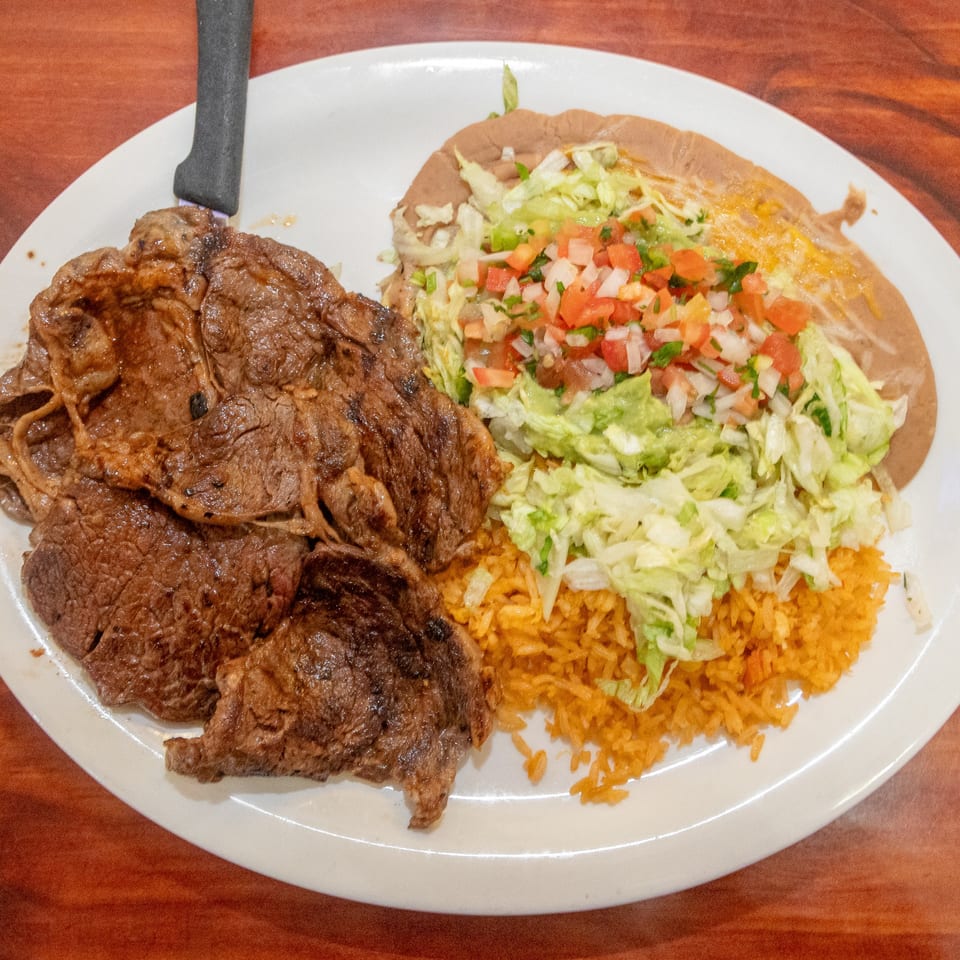 Mi Mexico's carne asada with rice, refried beans, guacamole, pico de gallo, and shredded lettuce.