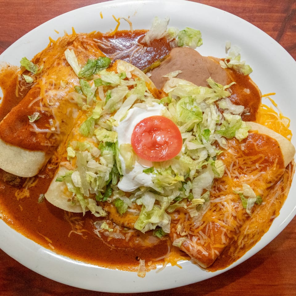 Mi Mexico Restaurant's enchiladas covered in red sauce, cheese, lettuce, sour cream, and a tomato slice.