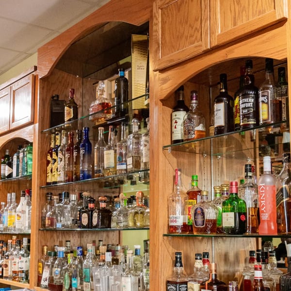A well-stocked bar at Mi Mexico Restaurant with various liquor bottles on wooden shelves.