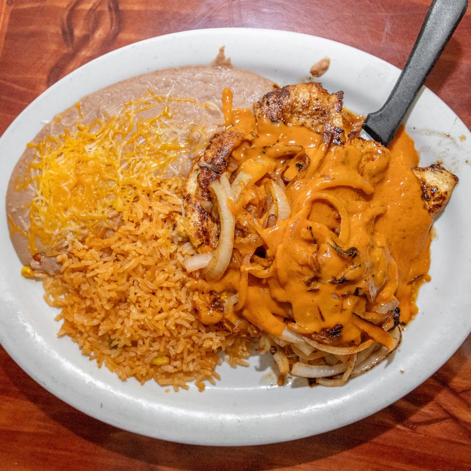 Mi Mexico's grilled chicken with orange sauce, onions, rice, and refried beans with cheese.