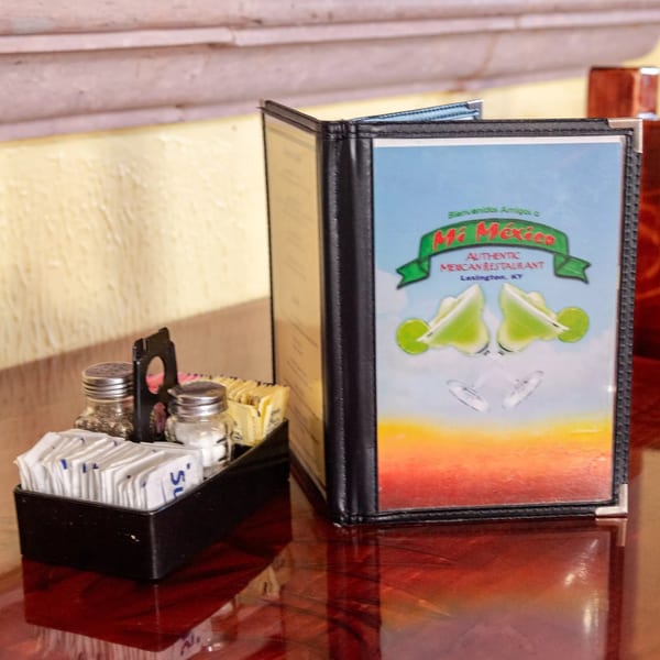 Mi Mexico Restaurant menu and condiment caddy on a glossy red table.