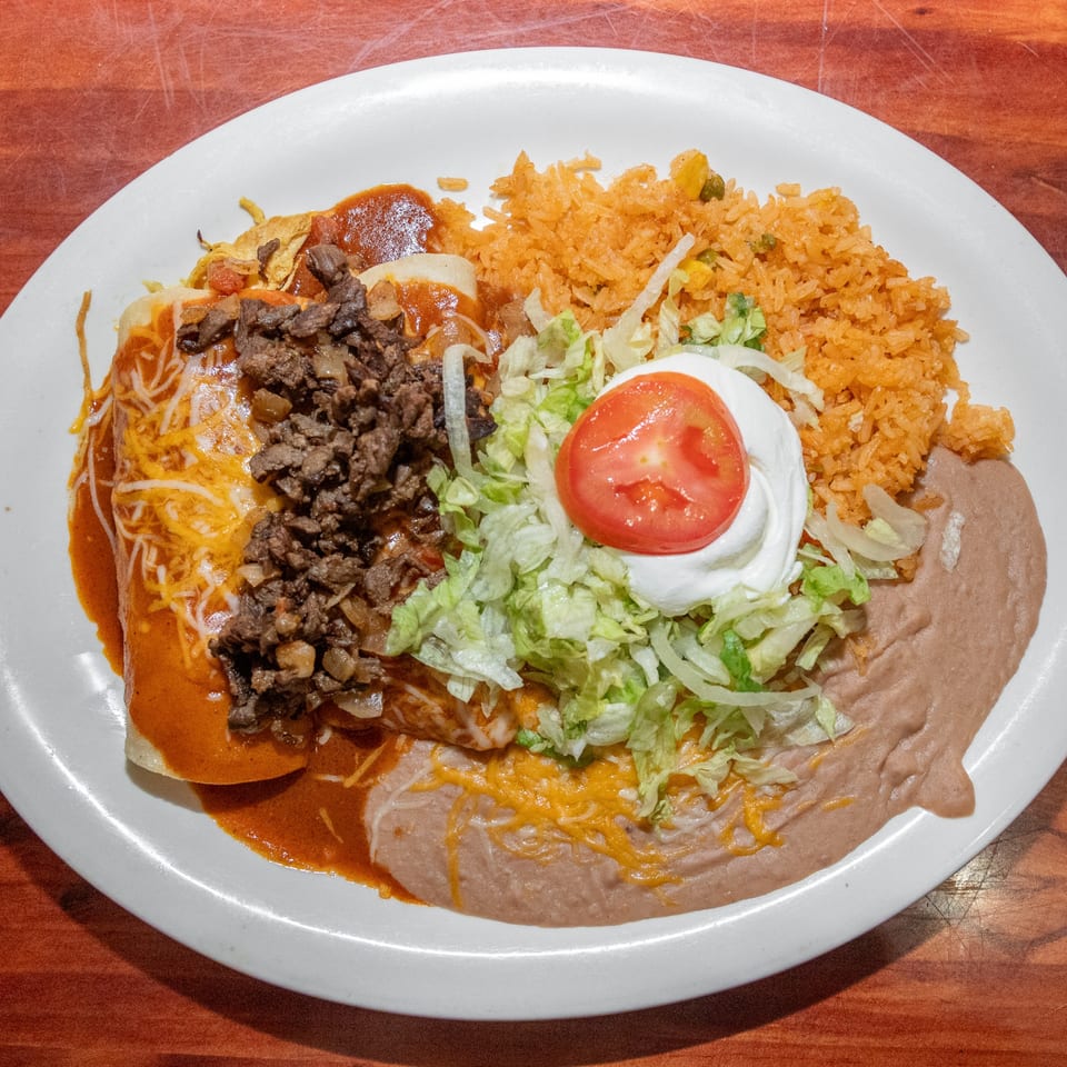 Mi Mexico Restaurant's Mexican combo plate with enchiladas, rice, refried beans, lettuce, sour cream, and tomato.